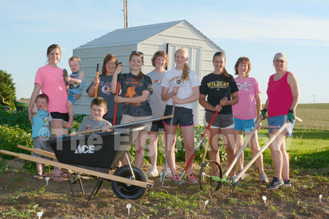 Posing in front of their new garden shed and with some of their new gardening tools are Cedar Creek club members and parents, l-r:  Sawyer Veik, Heather Veik, Myles Veik, Landyn Veik (in wheel barrow), Lori Beckman, Erin Beckman, Diane Nelson, Amy Nelson, Grace Henn, Sandi Henn and Anne Meis. The club was able to purchase the new equipment with grant monies recently received from Farm Credit Services of America’s “Working Here Fund”. E-R photo